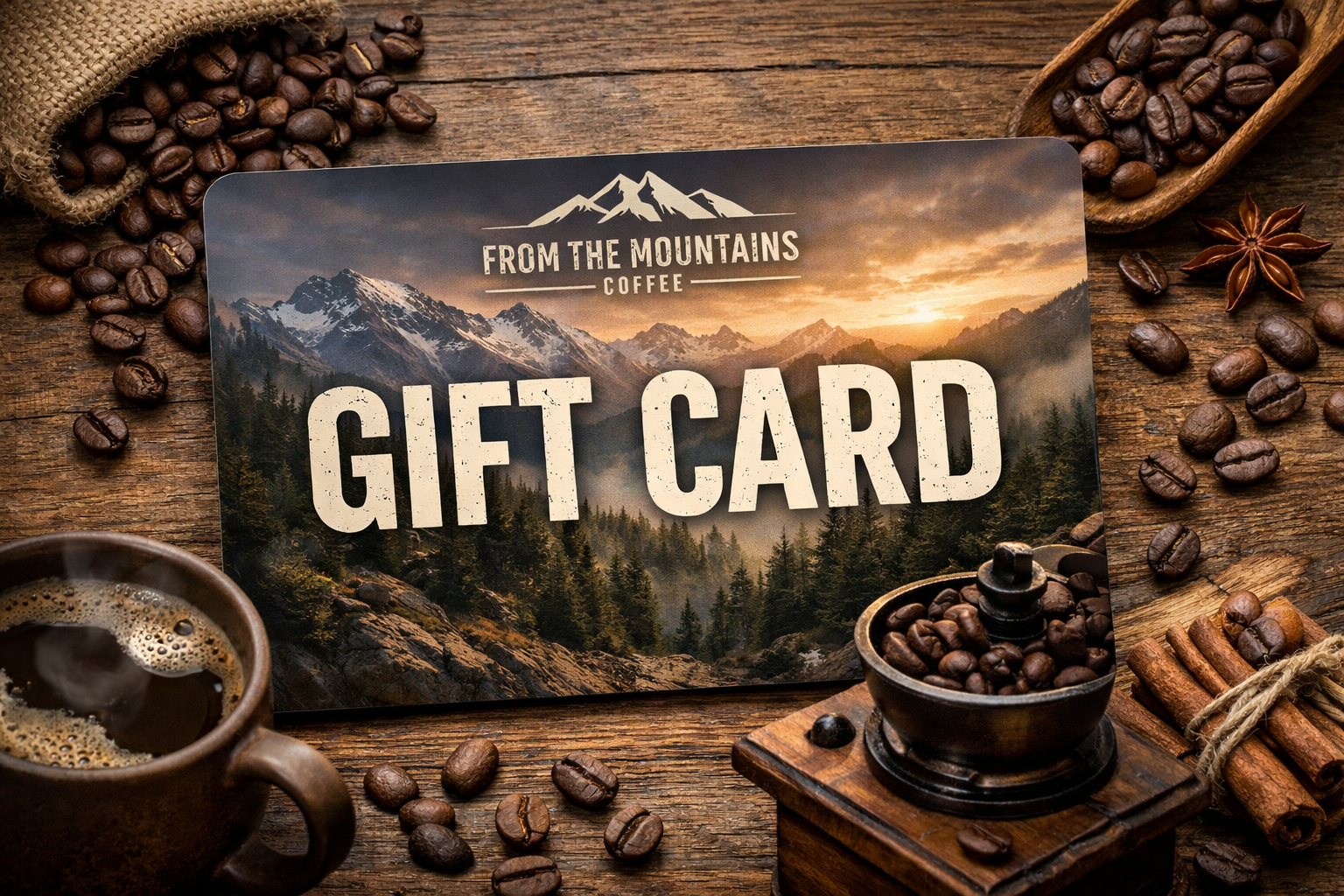 Gift card with mountain design surrounded by coffee beans, grinder, and cup on wooden surface